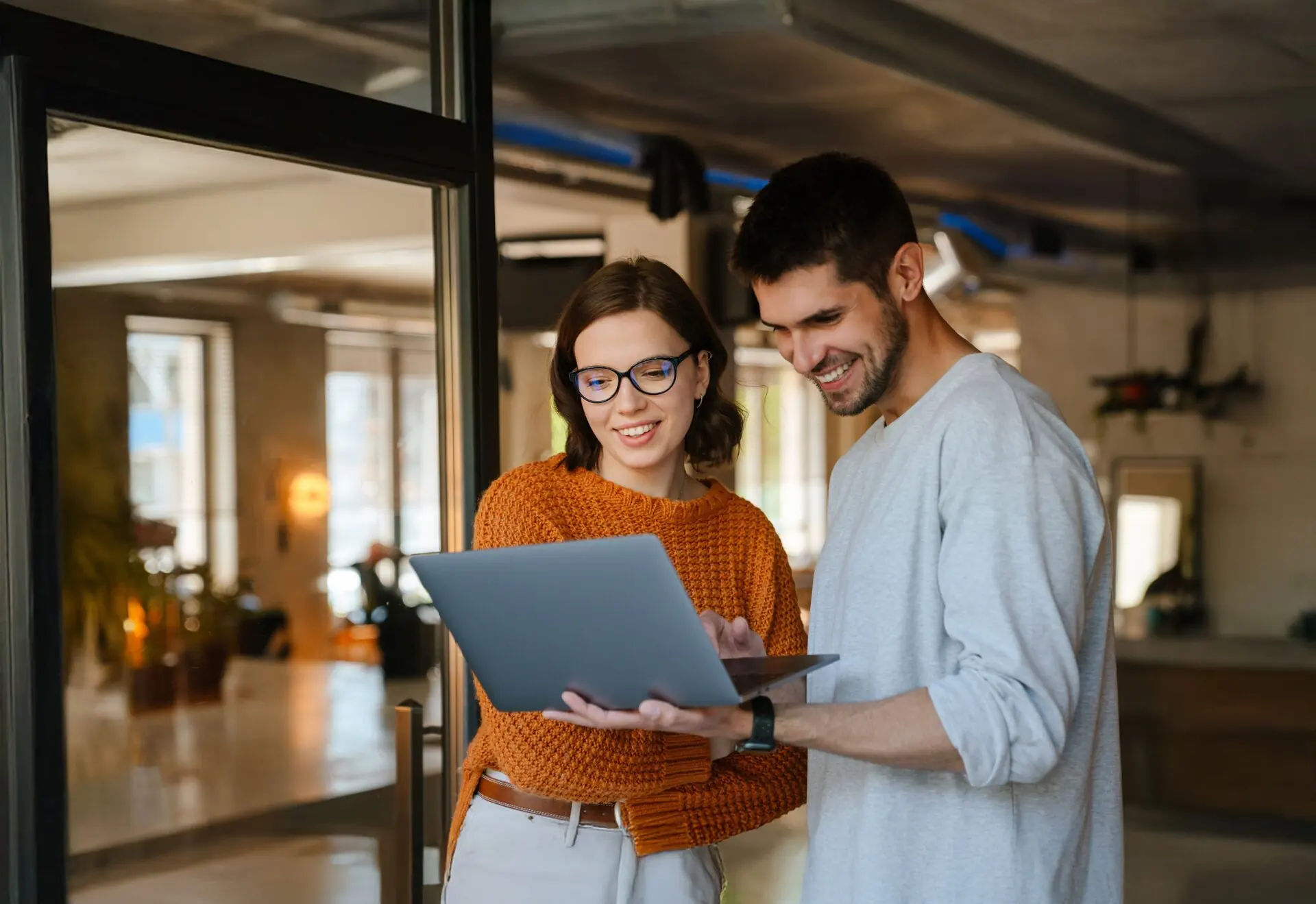 Two people looking at a laptop in an office doorway